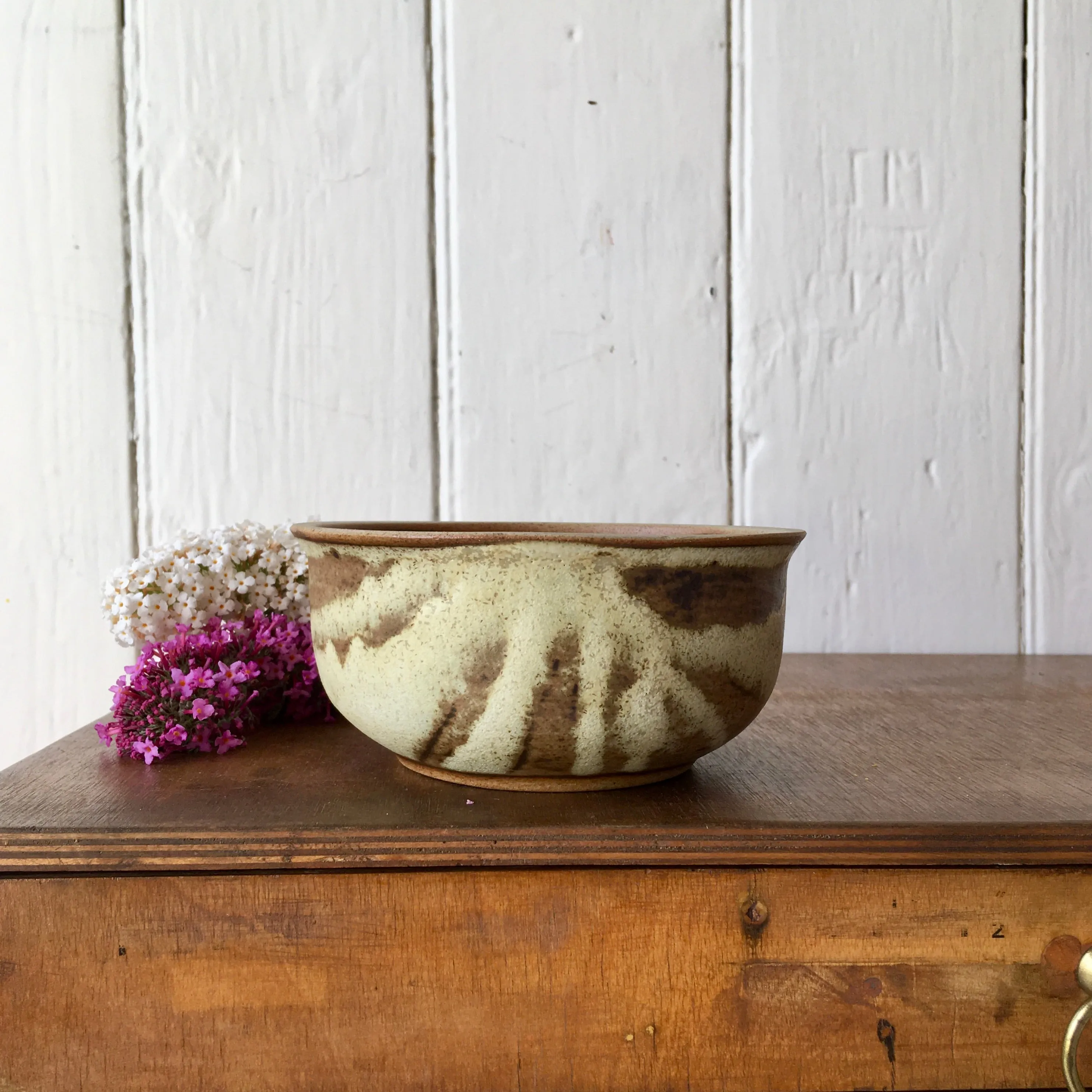 A hand-thrown stoneware studio pottery bowl with floral decoration