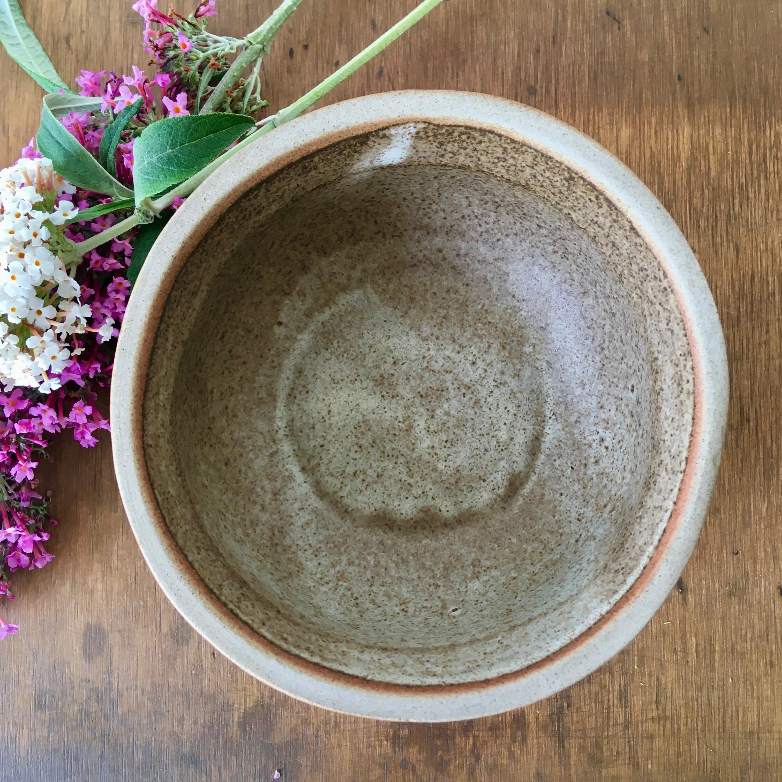 A hand-thrown stoneware studio pottery bowl with floral decoration